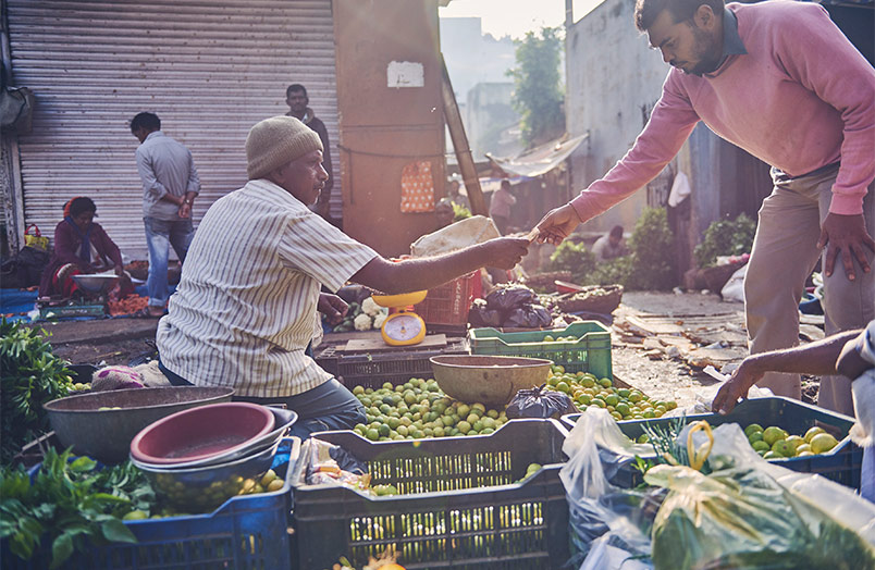 Mann bezahlt seinen Einkauf bei einem Verkäufer eines Straßenmarktes (Foto)